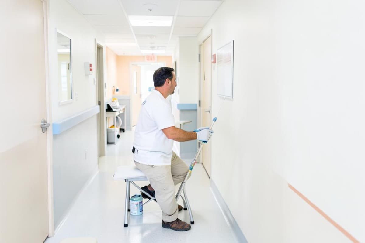 Painter rolling a corridor wall inside a healthcare building
