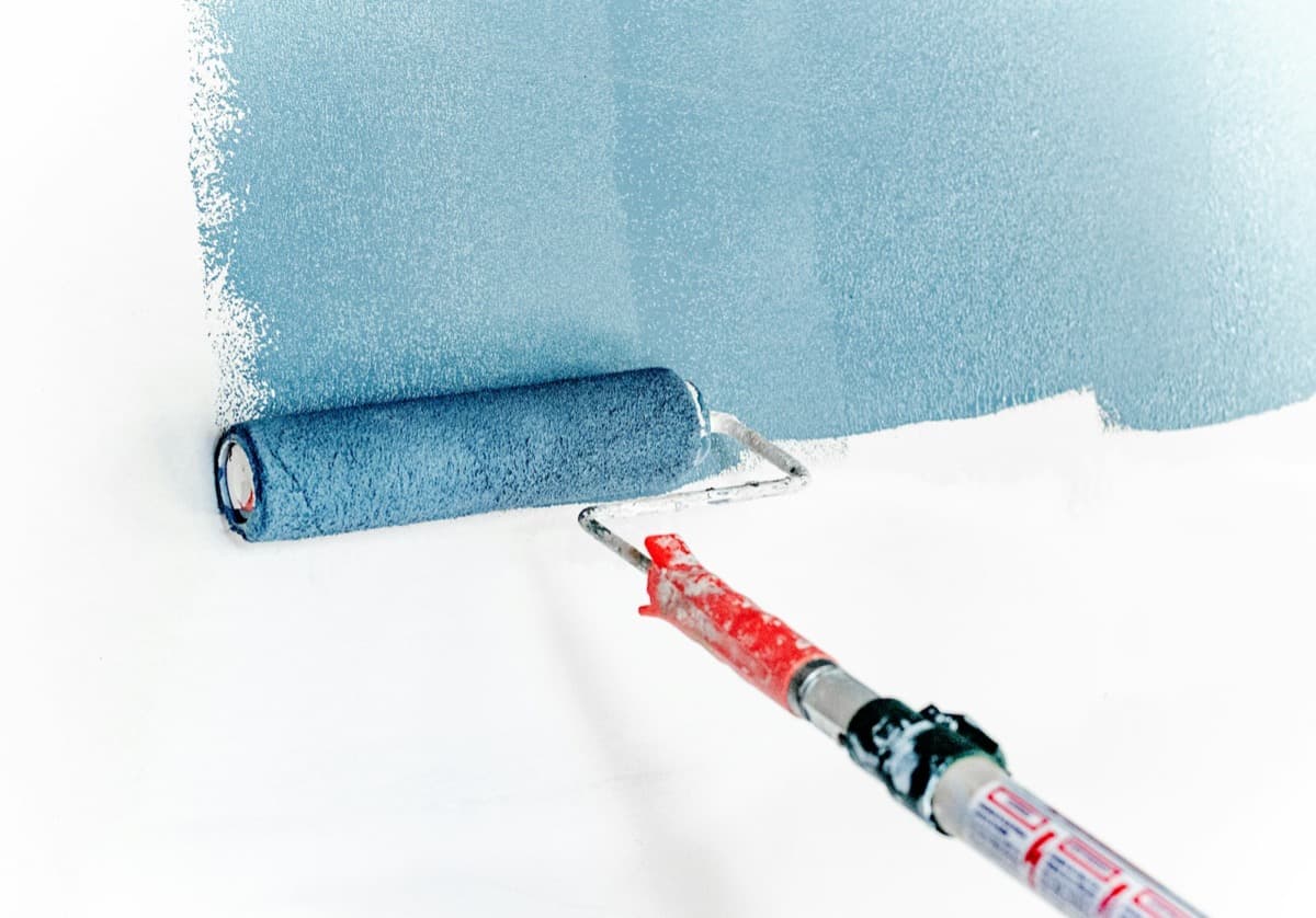 Roller laying fresh paint onto a wall, close-up