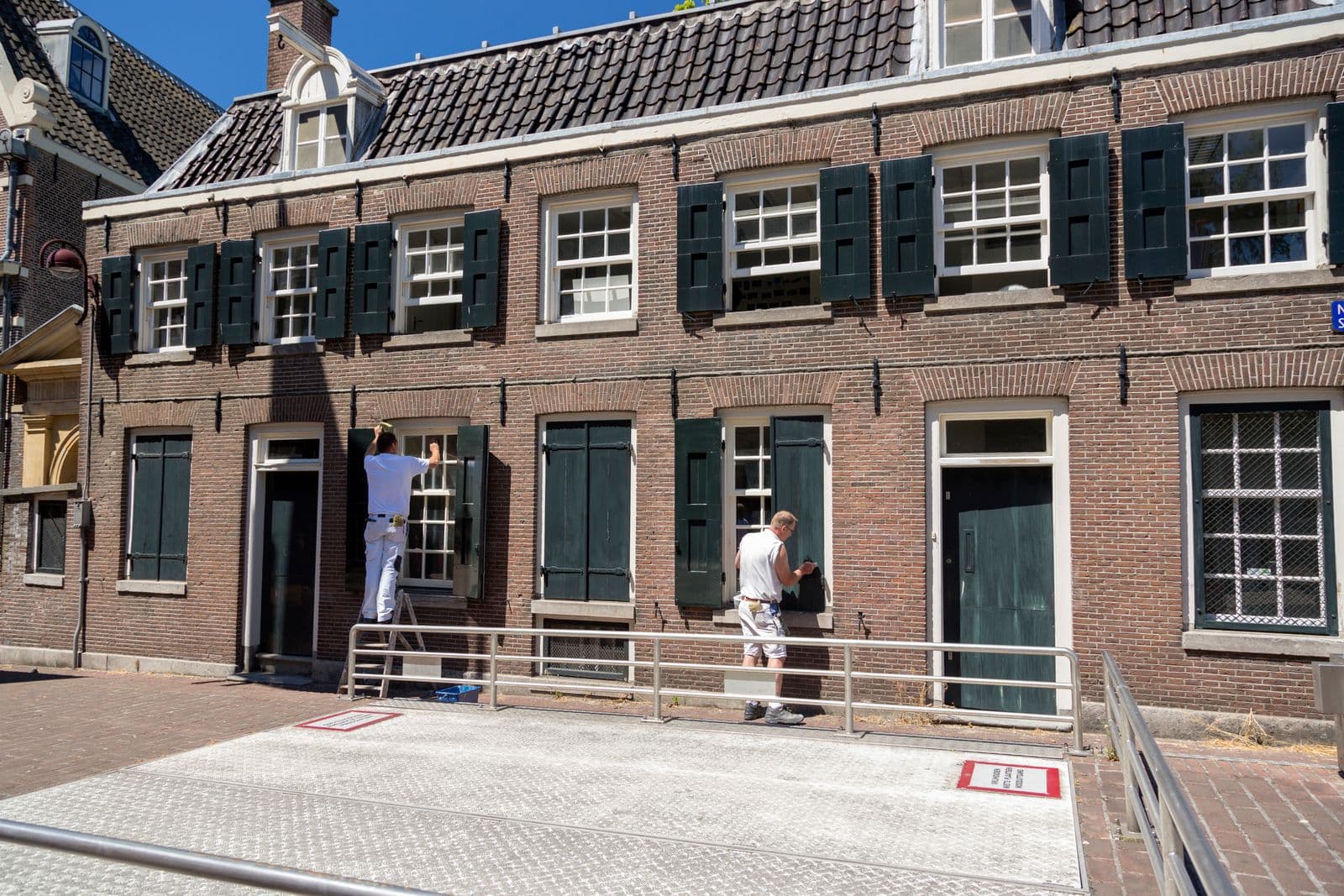 Two painters refinishing a brick house facade