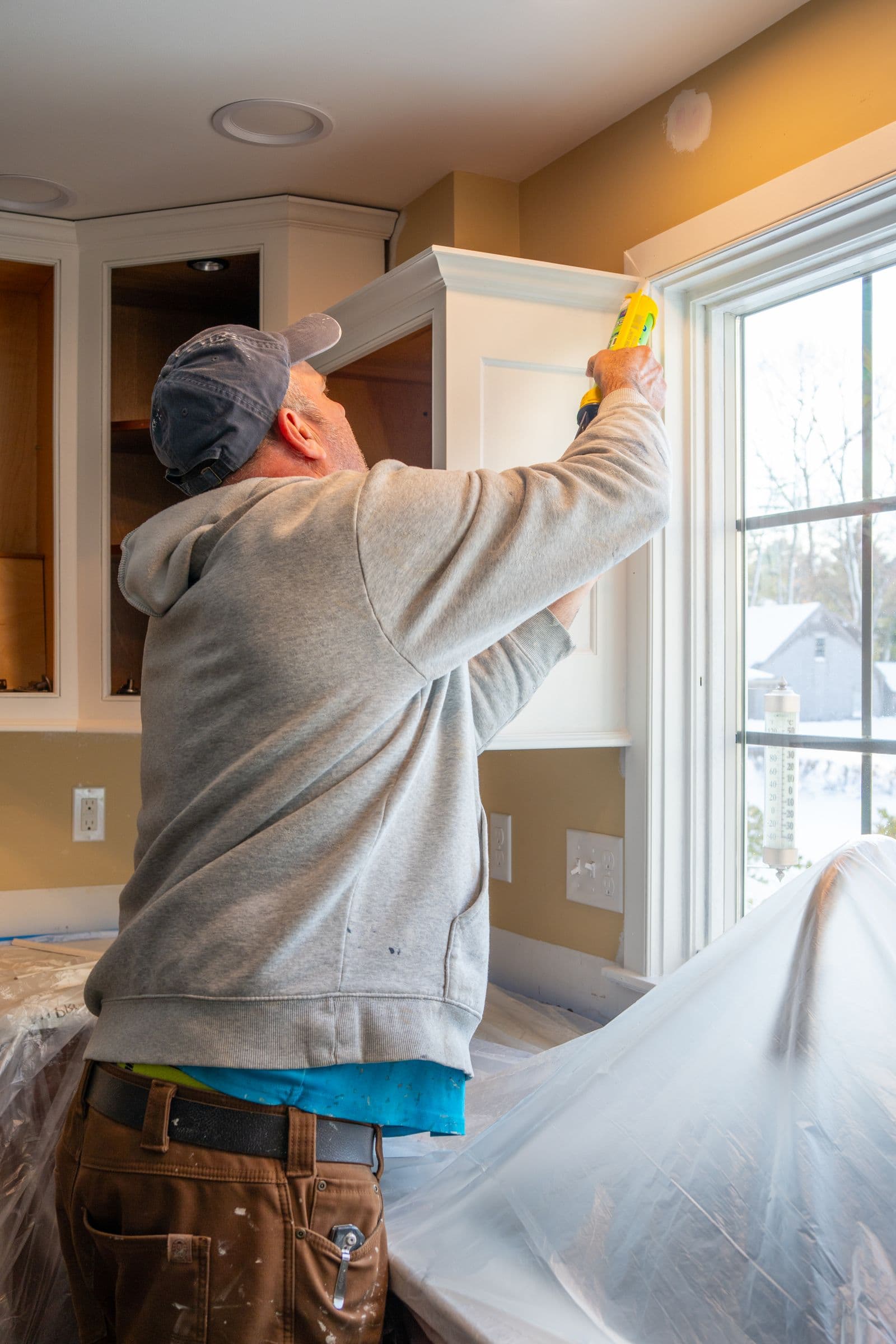 Painter caulking a seam with a caulk gun