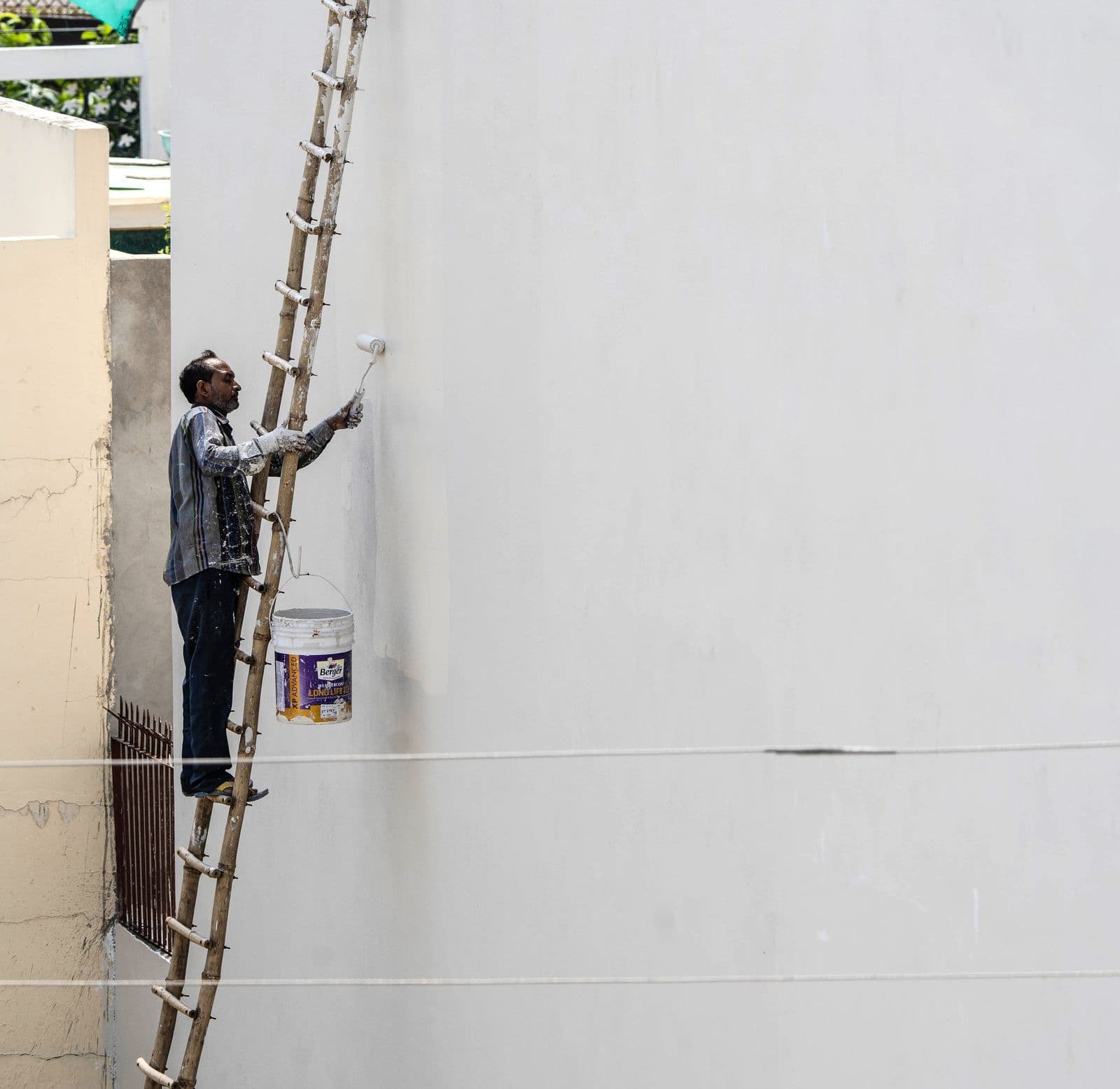 Painter on a ladder rolling an exterior wall